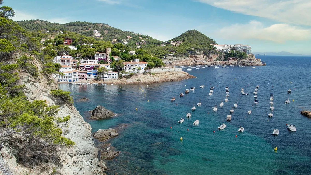 White houses and pine-covered hills around a bay full of small boats near Begur on the Costa Brava